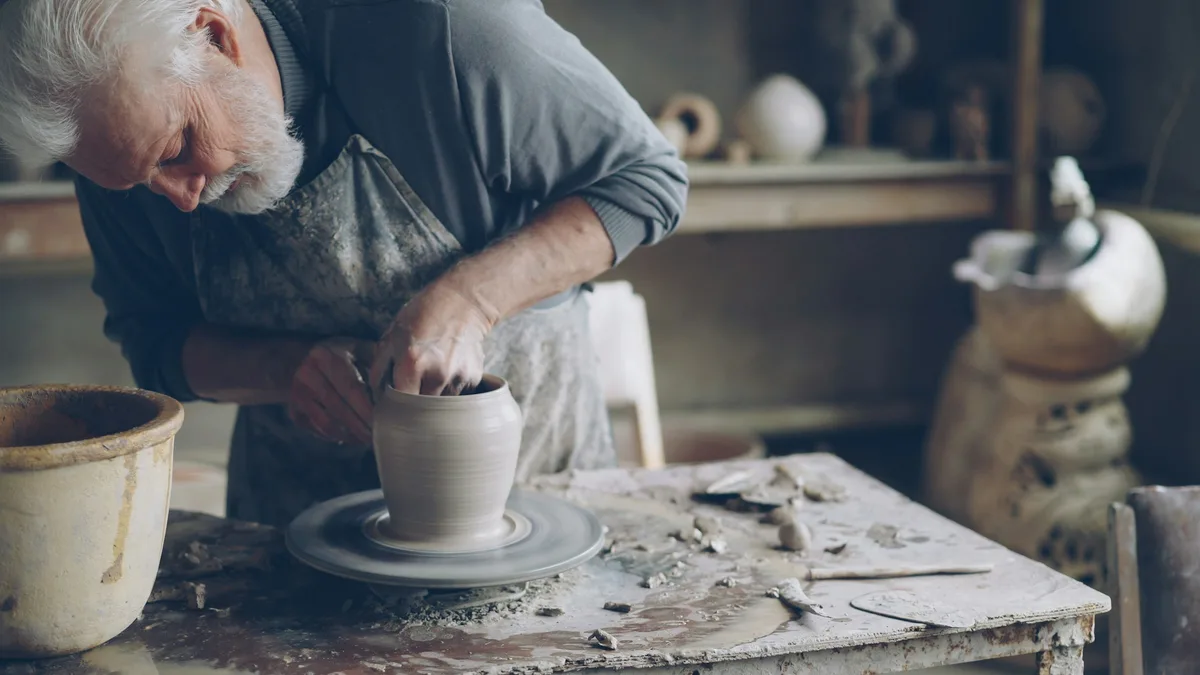 Artisan potter shaping clay on a wheel in his workshop